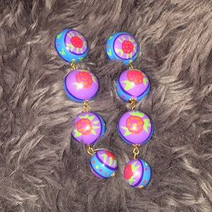 Long colorful earrings with flower details.